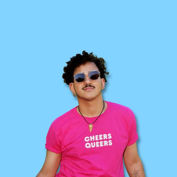 Mann traegt pinkfarbenes T-Shirt mit dem Aufdruck Cheers Queers
