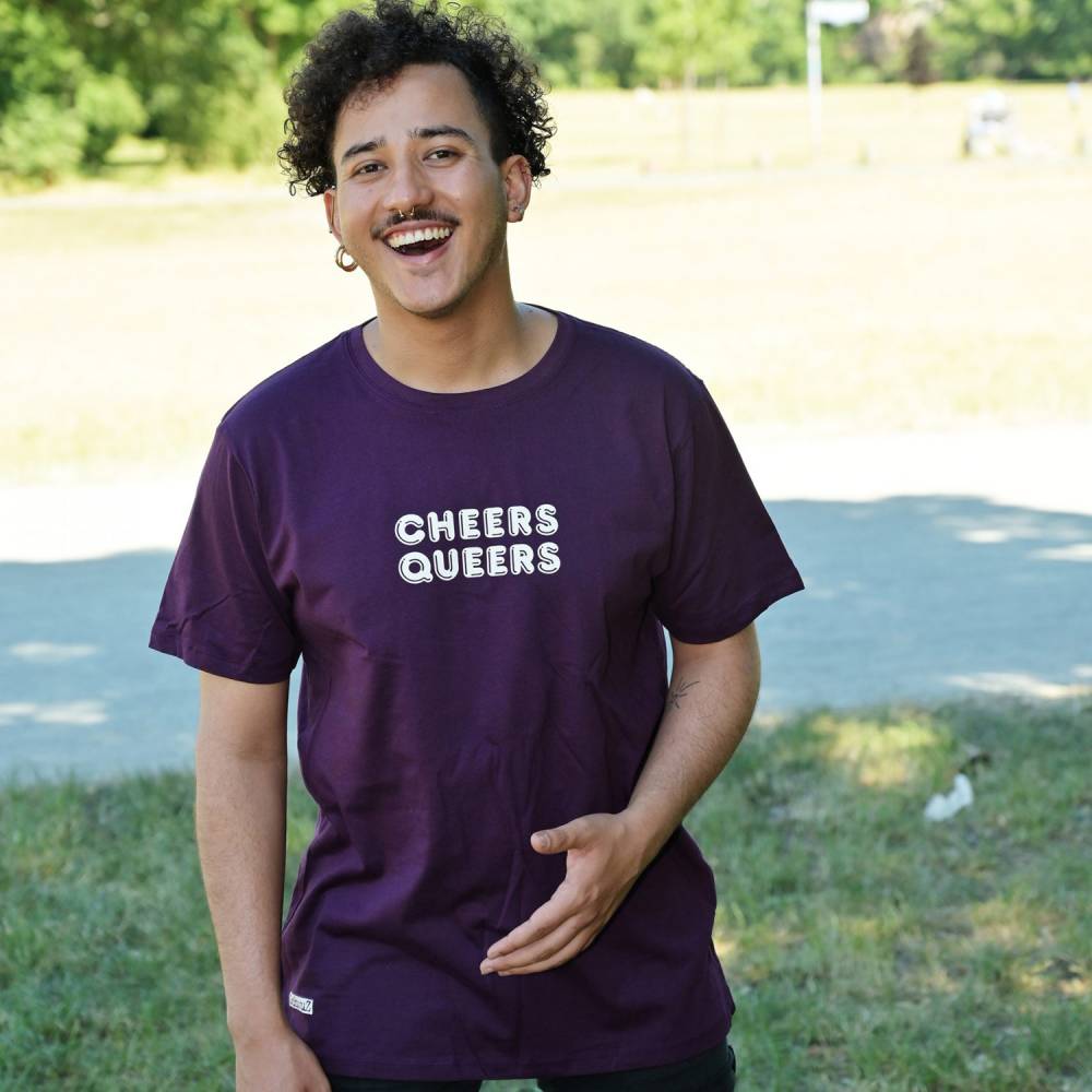 Mann traegt violettes T-Shirt mit dem Aufdruck Cheers Queers