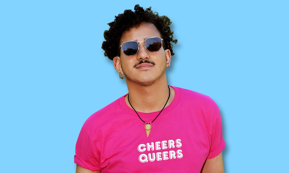 Person traegt pinkfarbenes T-Shirt mit der Aufschrift Cheers Queers