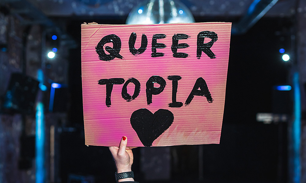 Selbstgebasteltes Schild mit der Aufschrift Queer Topia